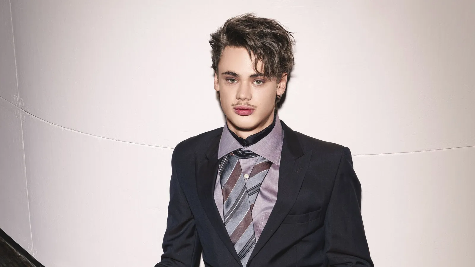 Einem jungen Mann fallen die voluminös gestylten Haare ins Gesicht.